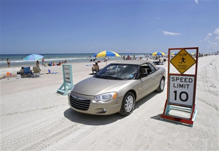 In this Aug. 19, 2010 photo, a car drives amongst beach goers in Daytona Beach, Fla. Safety concerns over cars driving on the beach have risen this year with the deaths of two 4-year-old children. (AP Photo/John Raoux)
